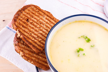 Cheese soup in a white plate with toasted bread