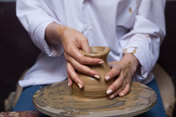 Hands of the master with clay. Ceramic workshop. Potter's wheel. Selective focus.