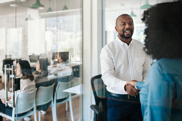 Smiling manager shaking hands with a new employee 