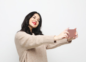 Fashion curvy brunette girl taking photo makes self portrait on smartphone