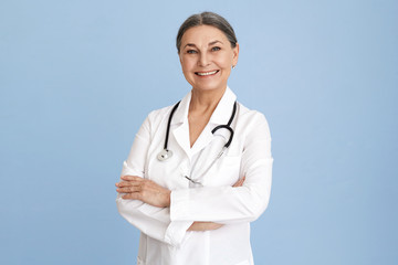 Isolated studio image of charismatic beautiful Caucasian senior female chief doctor crossing arms...