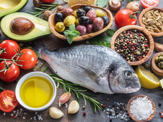 Raw dorado fish with spices and vegetables on the graphite board.