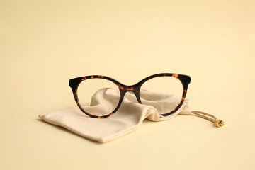 Modern fashionable acetate spectacles, torture color with textile beige bag laying on light yellow...