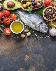 Raw dorado fish with spices and vegetables on the graphite board.