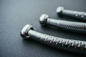 Obraz na płótnie Canvas Dental turbine handpieces tools without burs. Row of three professional instruments on gray background.
