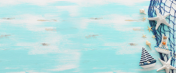 vacation and summer concept with vintage boat, starfish and seashells over pastel blue wooden...