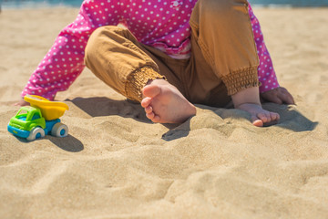 Kid's hand playing with a toy truck in the sand