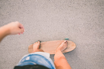 Beautiful young skater woman riding skateboard on the street, top view