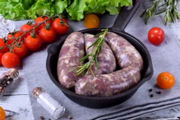 Raw meat sausages in a natural shell in a cast iron pan prepared for grilling