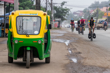 Eco-friendly electronic tuk tuk in Luang Prabang, Laos. Green and yellow vehicle. Car rickshaw in...