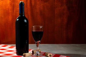 Bottle of red wine in wine cellar for tasting. Red wood background. Wine tradition and culture...