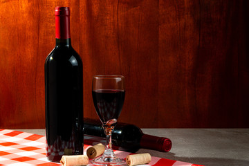 Bottle of red wine in wine cellar for tasting. Red wood background. Wine tradition and culture...