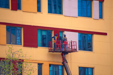 two men wash windows in a building standing high on the platform