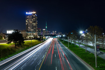 Light trails from cars driving down Lake Shore Blvd, heading towards downtown Toronto. City Skyline in the distance