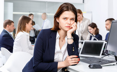 Portrait of unhappy girl in modern open plan office on background with coworkers