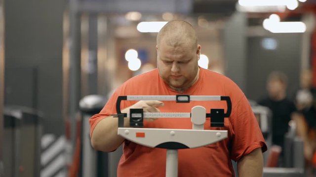 Attractive and overweight man standing on a mechanical scale