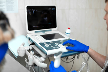 A veterinarian does an ultrasound of the dog's eye in the office. Male doctor's hand on an ultrasound machine close-up..Veterinary clinic background