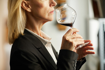 Side view closeup of female sommelier holding wine glass during tasting session, copy space