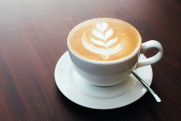 Freshly brewed cappuccino in a cup of white color on a wooden table in the morning during breakfast