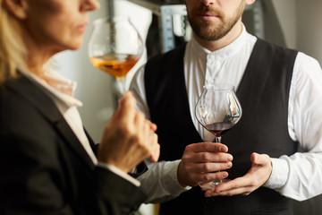Mid section portrait of two professional sommeliers examining wine during tasting session, copy space
