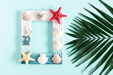 Sea beach composition. Starfish, seashell, photo frame, tropical green leaves of palm tree on pastel blue background. Summer concept. Flat lay, top view, copy space