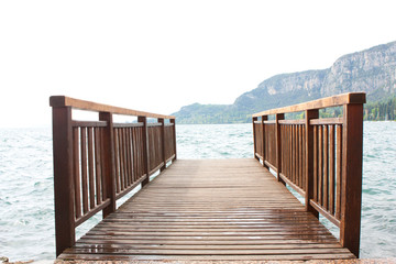 Wooden bridge, lake and mountains at the background.