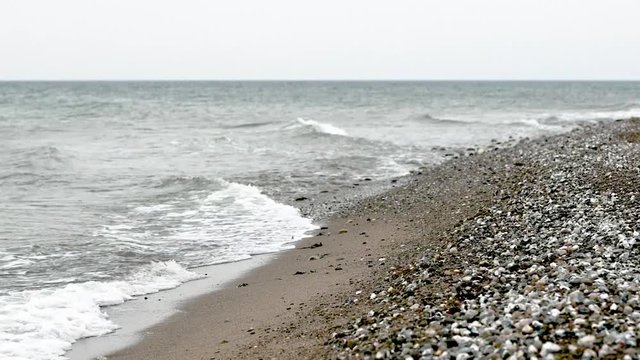 Wellen mit Brandung am Kiesstrand mit Kies