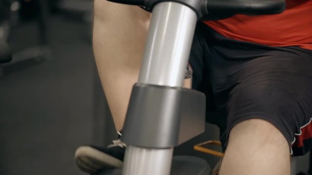 Close up pf mans knee cycling on bike in gym