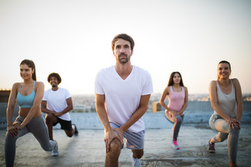 Group of happy fit friends exercising outdoor in city