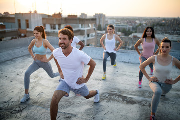 Group of happy fit friends exercising outdoor in city