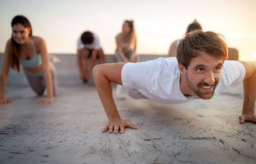 Group of happy fit friends exercising outdoor in city