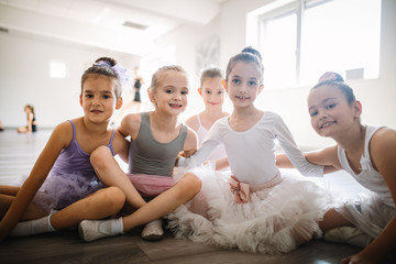 Group of fit happy children exercising ballet in studio together