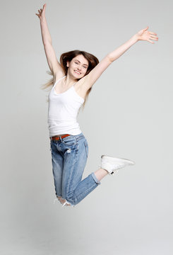 Smiling Young Woman Jumping In Air Over White  Background 