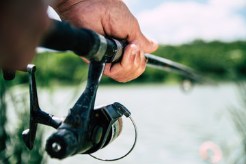 Hands of an old fisherman holding fishing rod