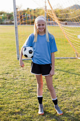 Portrait of smiling girl with soccer ball standing on grassy field © Cavan for Adobe