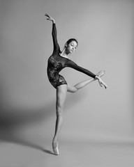 Beautiful ballerina in pointe shoes and colorful clothes posing. Black and white photo.