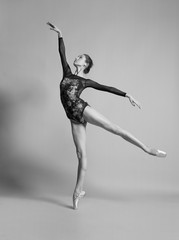 Beautiful ballerina in pointe shoes and colorful clothes posing. Black and white photo.