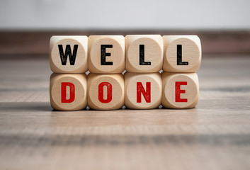 Cubes and dice with messages Good Work and Well Done on wooden background