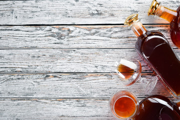 A bottle of cognac and glasses on a white wooden background. Brandy. Top view. Free space for your text.