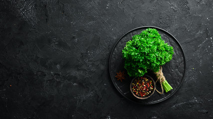 Fresh green parsley. Spices and herbs. On a black stone background. Top view. Free space for your text.