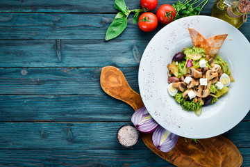 Vegetable salad with mushrooms, olives and feta cheese. In the plate. Top view. Free space for your text. Rustic style.