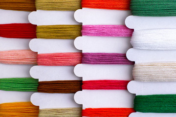 Colored embroidery threads on spools in a row ready for cross stitch.