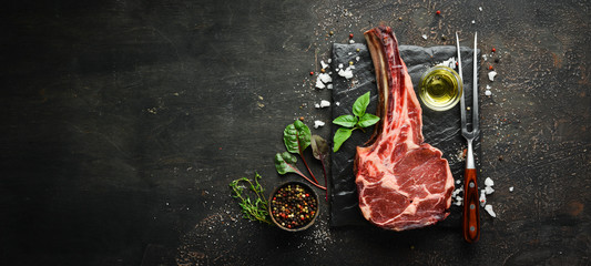 Raw dry steak tomahawk on a black background. Steak Cowboy. Barbecue. Top view. Free space for text.