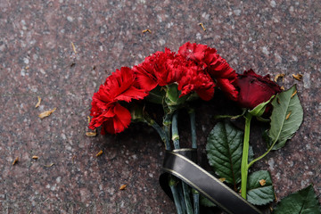 Red carnations flowers and rose seen on the memorial stone