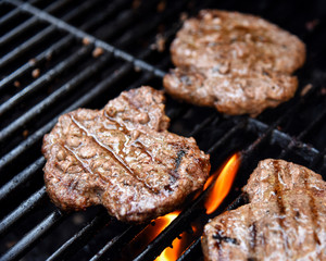 Grilling burgers on a barbecue closeup with flames