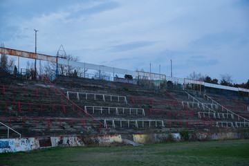 Fototapeta premium Abadoned Stadion Za Luzankami is a currently inactive stadium in Brno, Czech Republic. Captured in spring sunset, sky and clouds was colored to blue dark colors. Photo from tribunes and inside middle