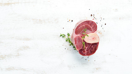 Raw fresh cross cut veal shank with spices and herbs on a white background. Cheese Bif steak Ossbo. Top view. Free space for your text. - obrazy, fototapety, plakaty