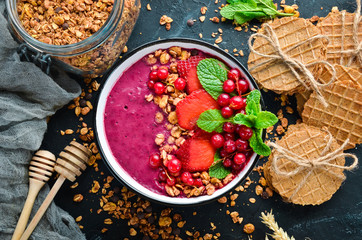 Smoothie bowl with granola, strawberry, red currants and mint. Breakfast. Top view. Free space for your text.