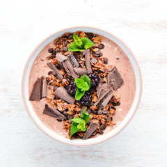 Fresh breakfast with yogurt, granola, chocolate and berries in a bowl. Top view. Free space for...