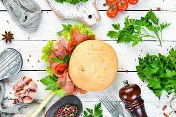 Burger with Prosciutto on old wooden background. Breakfast. Top view Free space for your text.